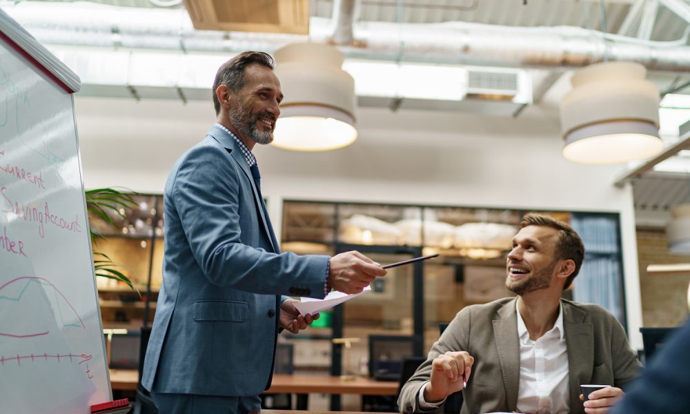 mature-business-coach-or-speaker-make-flip-chart-presentation-to-diverse-businesspeople-at-meeting.jpg